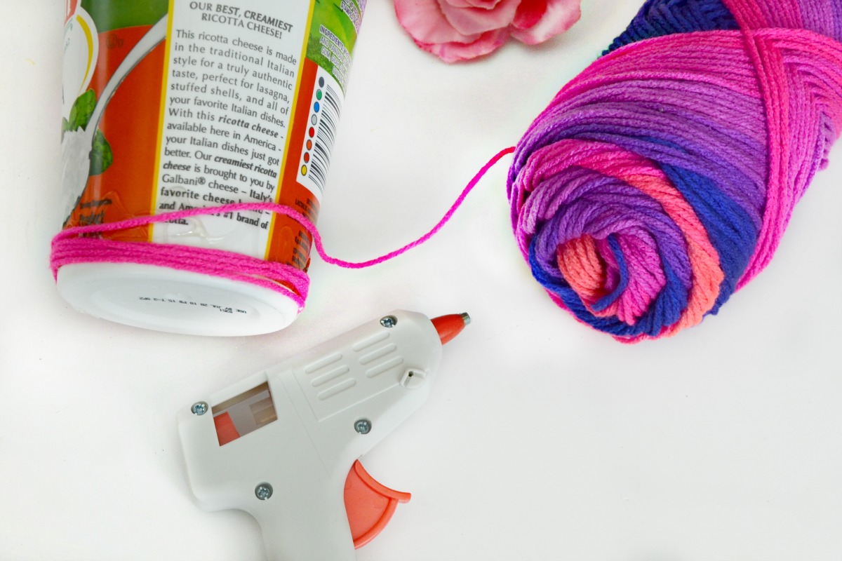 Multicolor yarn wrapped around a plastic food container makes a fun unicorn desk organizer.
