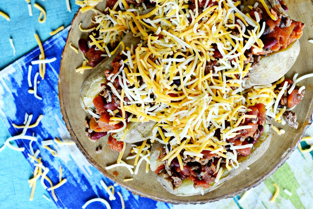 Top your chili baked potatoes with cheddar cheese for a yummy fall meal!